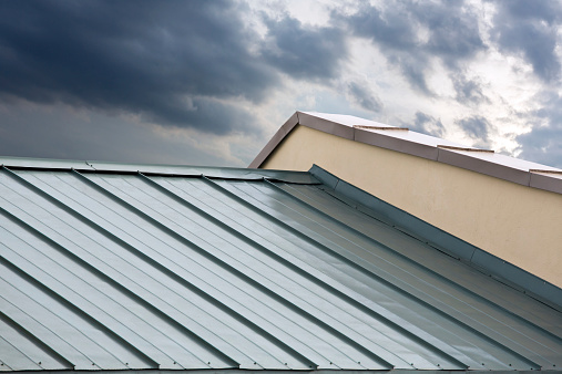 Standing seam roof panels meeting a wall with metal flashing