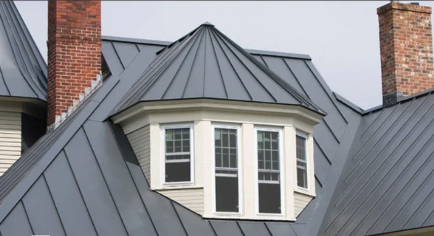Gray standing seam roof with a bay window, dormer and chimneys